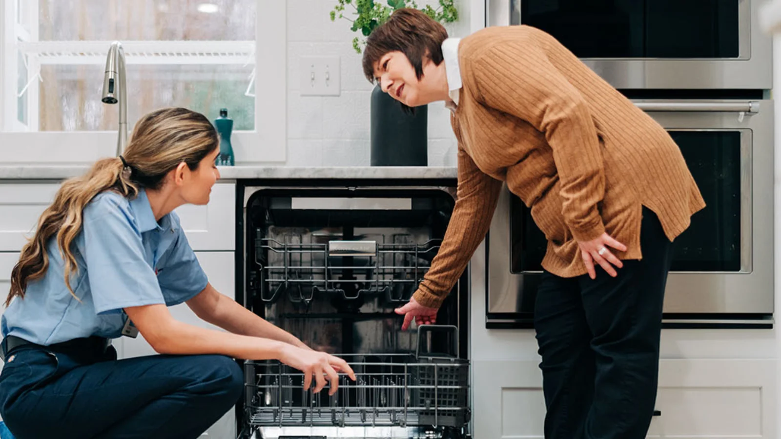 Female technician offering same-day appliance repair in Tampa while inspecting a customer’s dishwasher.