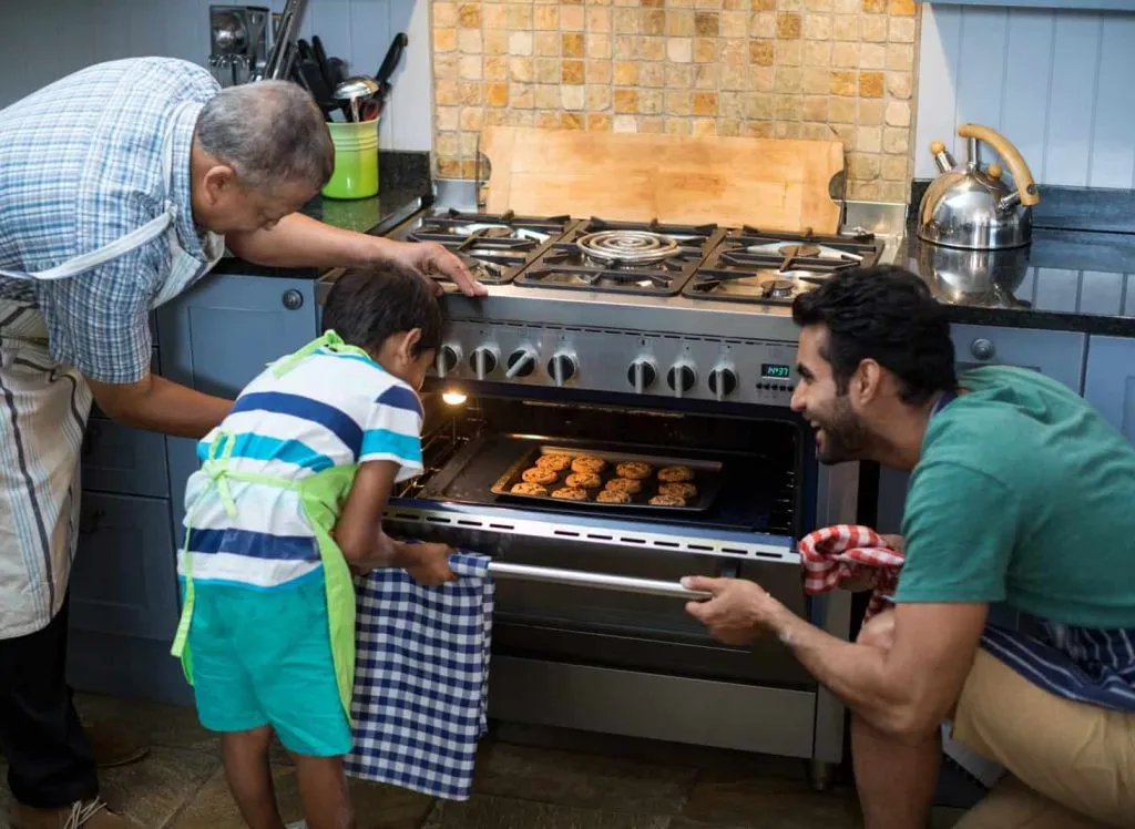 Family keeping cookies in oven at home